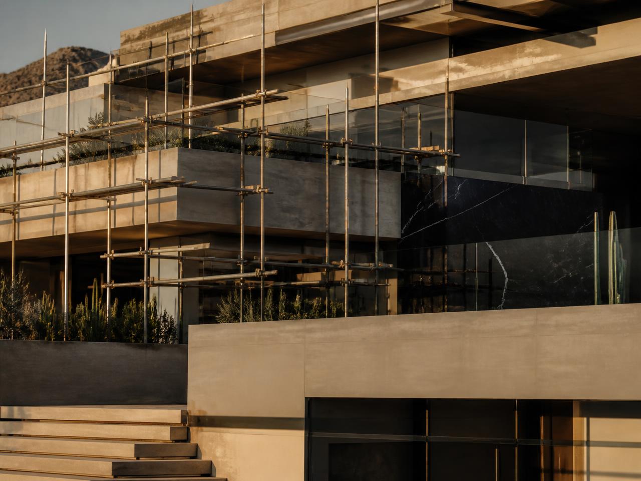 Residencia contemporánea en proceso de construcción con andamios y luz dorada